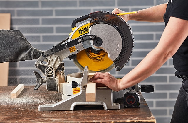 Person cutting wood using a mitre saw