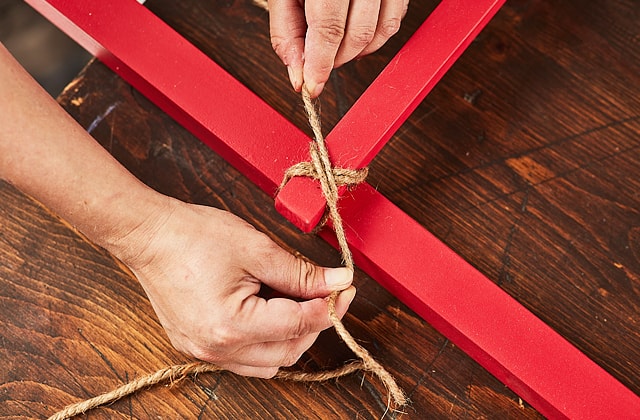 Person tying burlap around a red ladder