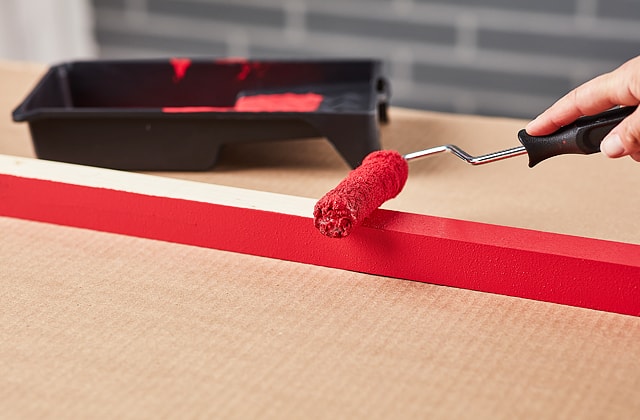 Person applying red paint with a roller