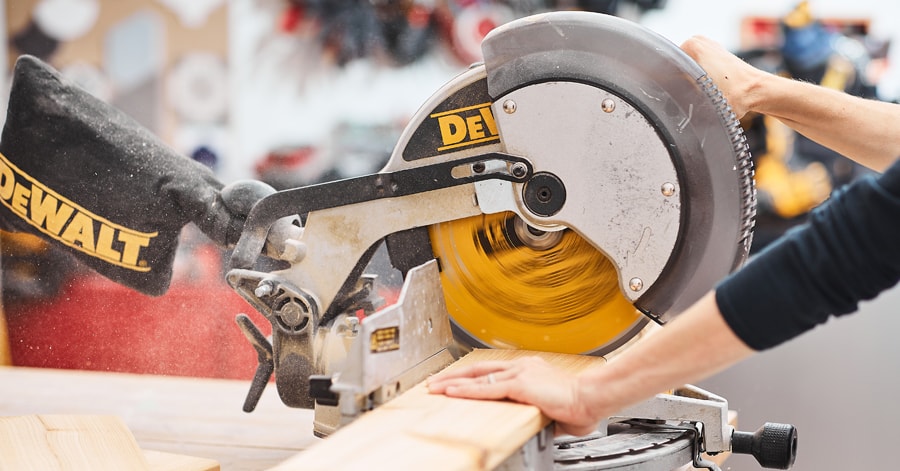 Person cutting wood planks using a mitre saw
