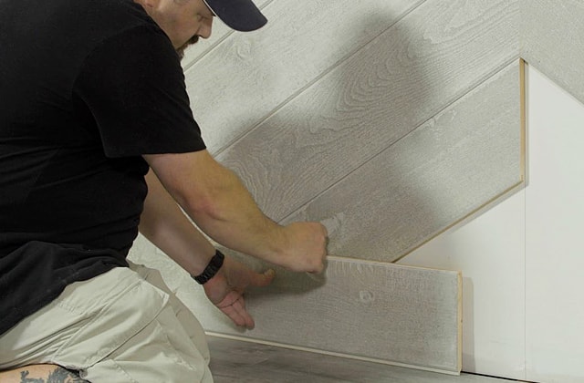 Person tracing a cut line using a wood plank