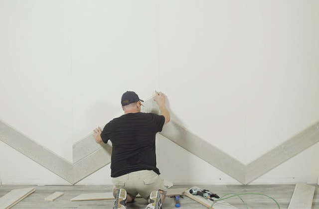 Person installing barn wood planks on a wall