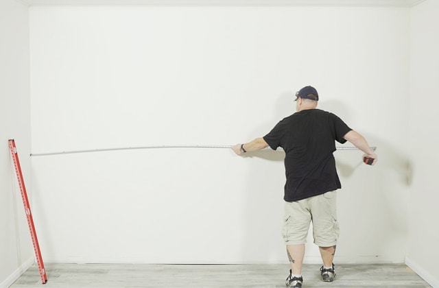 Person measuring a wall with a measuring tape