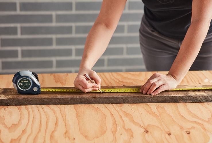 Personne mesurant une planche de bois Personne mesurant une planche de bois