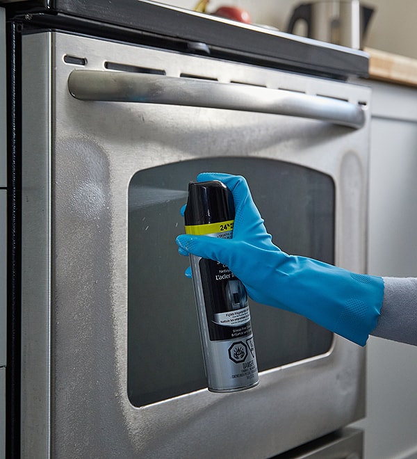 Person cleaning a stainless-steel oven Person cleaning a stainless-steel oven