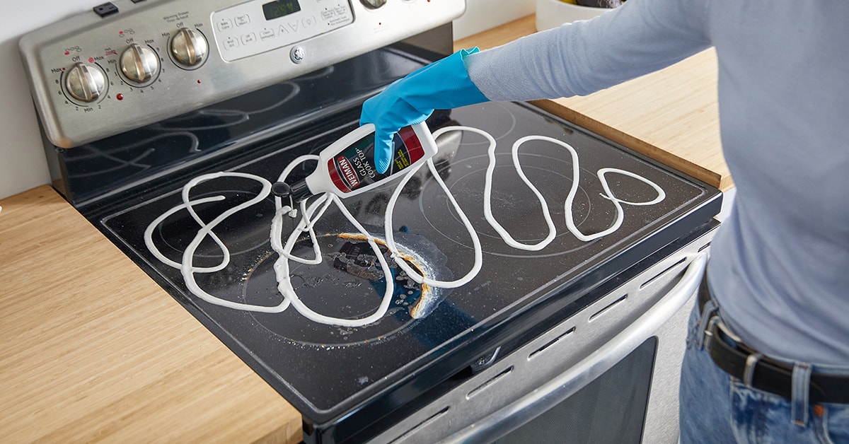 Person cleaning a glass stovetop Person cleaning a glass stovetop