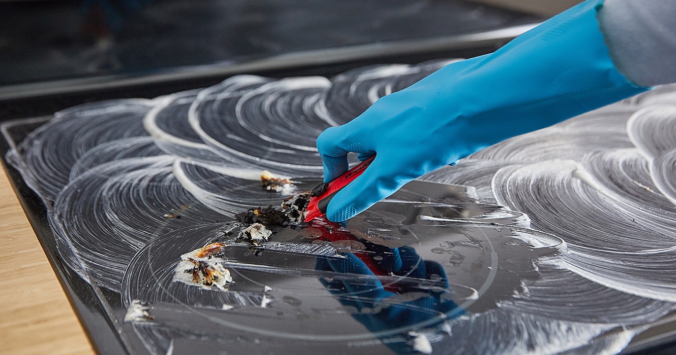 Person scrubbing a glass cooktop