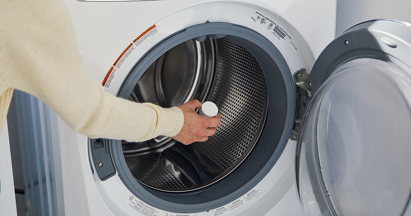 Person placing a cleaning tablet in a washer tub
