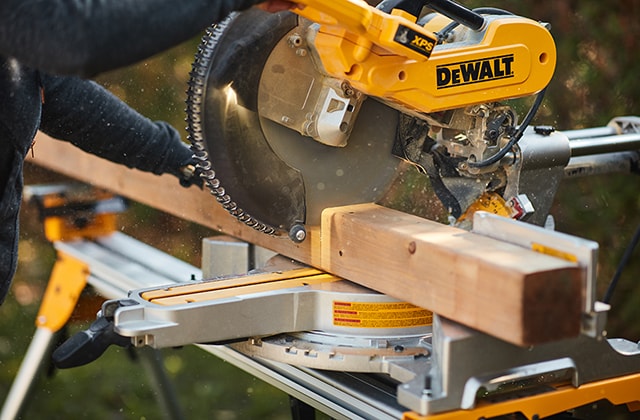 Person using a mitre saw to cut a wooden post