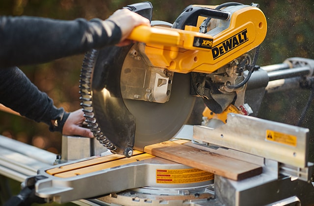 Person cutting a wood slat with a mitre saw
