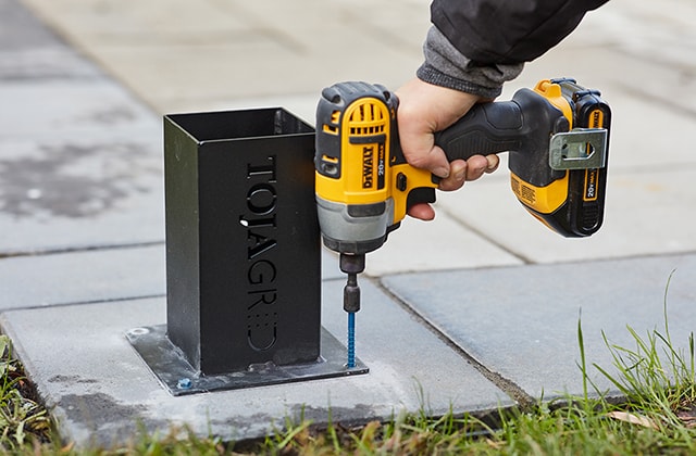 Person securing a post base on a concrete slab