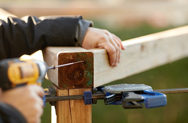 Person using a drill to secure a wooden post