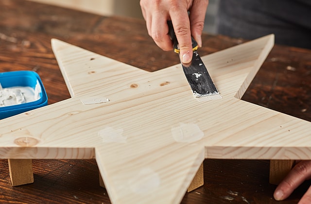 Person applying wood filler with a putty knife