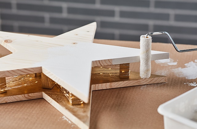 Person applying white paint with a roller