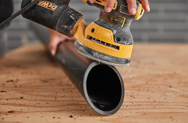 Person sanding the end of a pipe