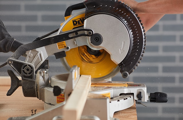 Person cutting wood planks with a mitre saw
