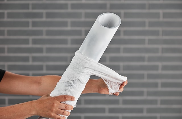 Person wrapping gauze around a pipe