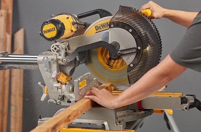 Person cutting wood with a mitre saw