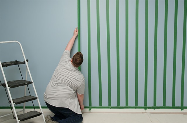 Man applying painter’s tape on a wall