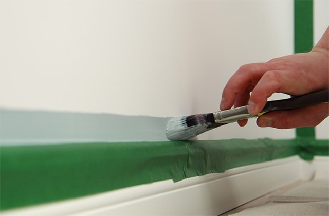 Man trimming moulding with blue paint