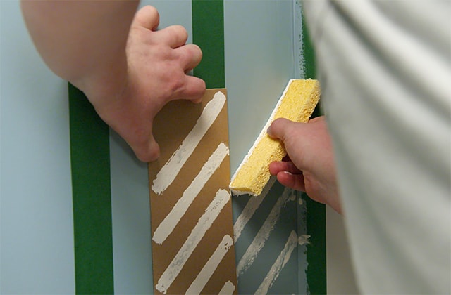 Person using a template to create a wall pattern