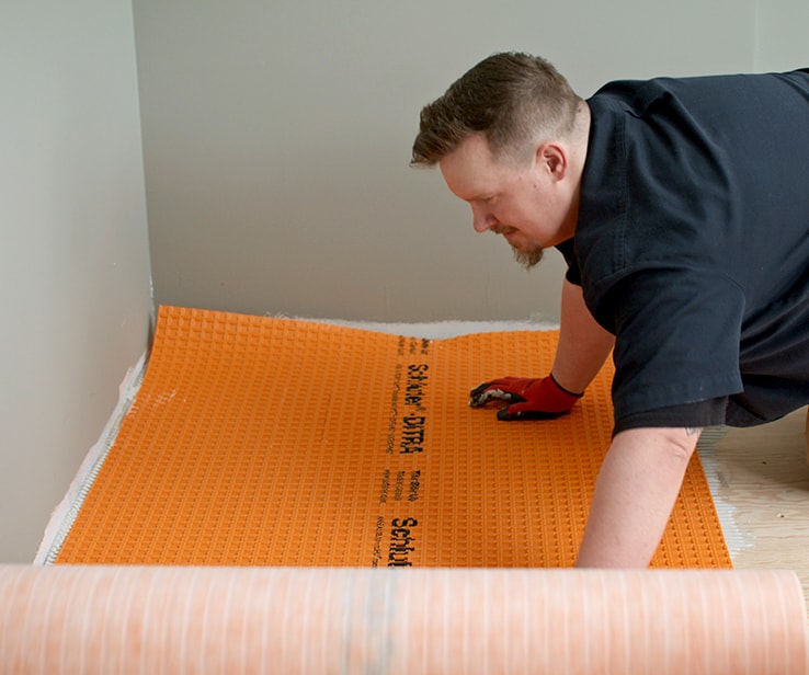 Person laying a membrane onto the floor