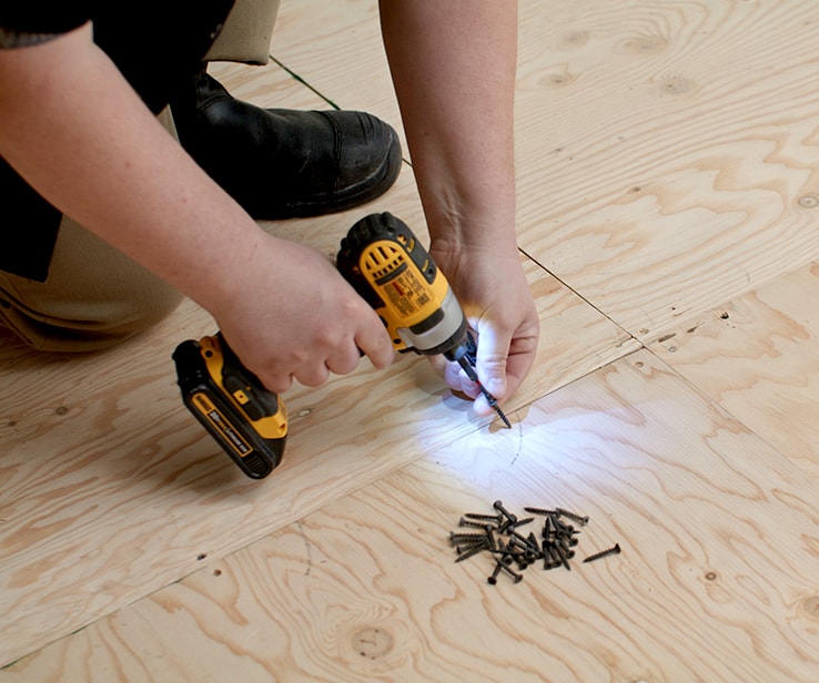 Person solidifying a plywood subfloor