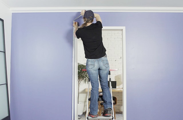 Personne qui mesure un mur