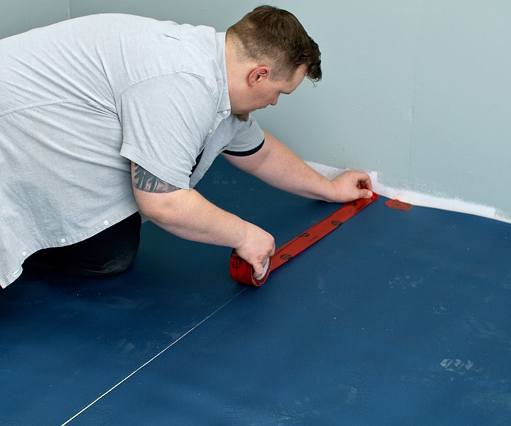 Person taping a membrane onto the floor