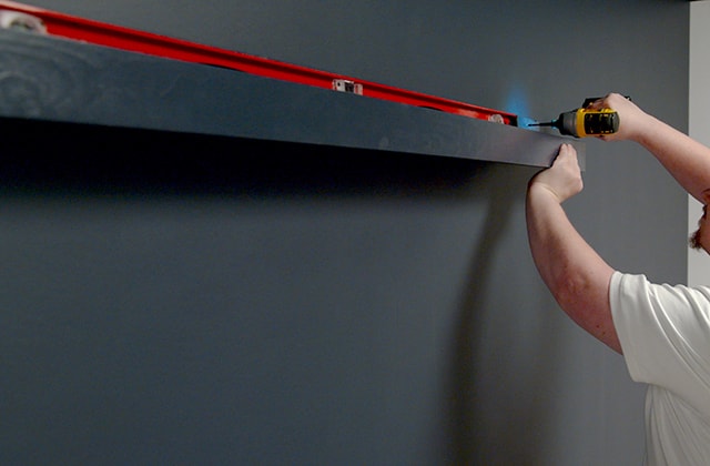 Man checking that a wall shelf is level