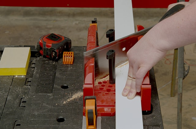 Man cutting a moulding with a hand saw