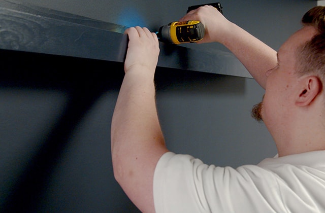 Man securing a wall shelf in place