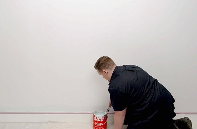Person trimming a wall with paint