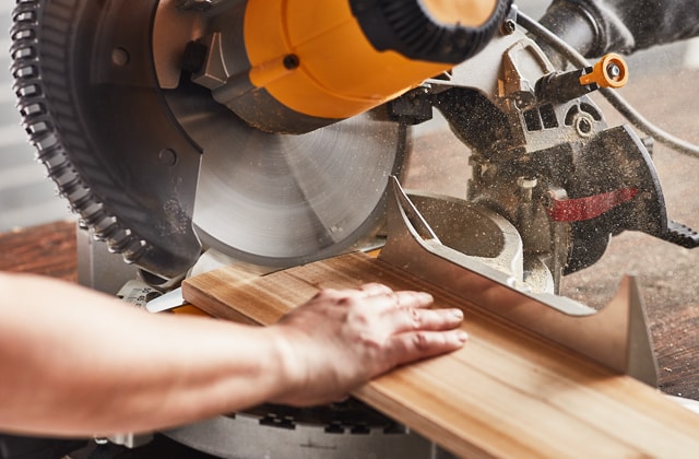 Person cutting wood using a mitre saw