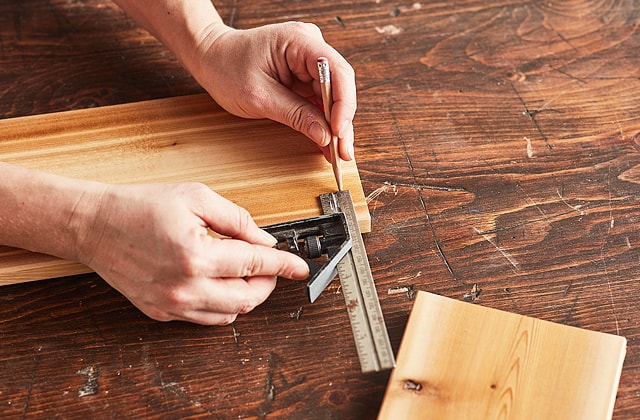 Person using a square to mark measurements