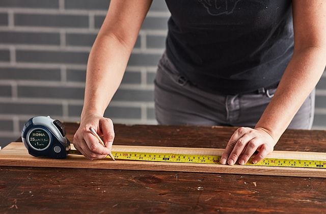 Person measuring a wood plank