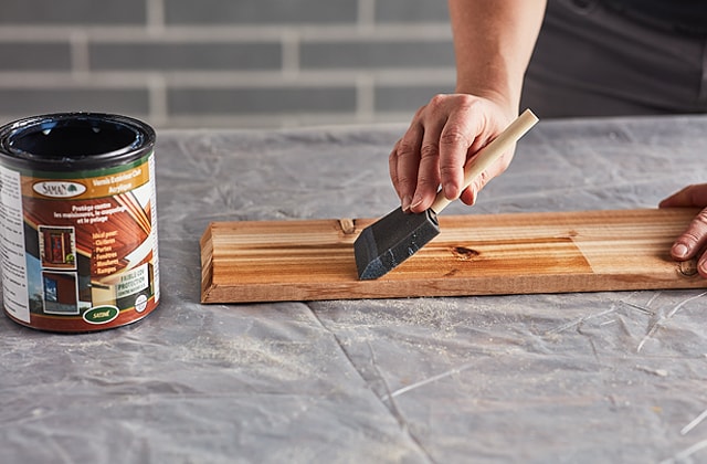 Person applying varnish to a piece of wood