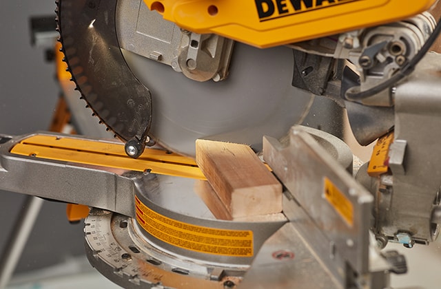 Person using a mitre saw to cut wood at an angle