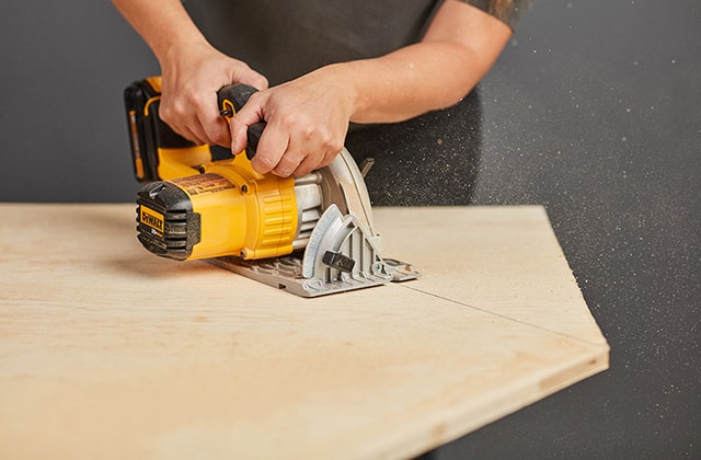 Person cutting a plywood sheet with a circular saw