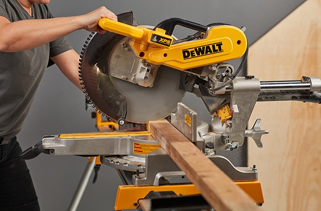 Person cutting a piece of wood using a mitre saw