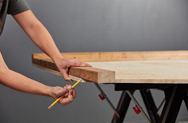 Person tracing an angle to cut on a piece of wood