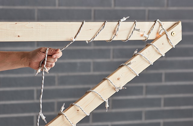 Person wrapping string lights around a wooden star