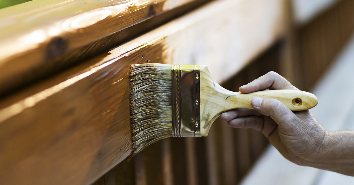 Brush applying stain to a wooden deck
