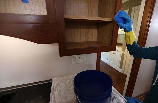 Person cleaning kitchen cabinet frames