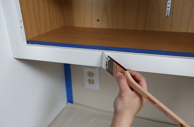 Person painting cabinet frames white