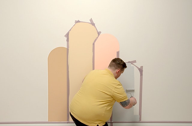 Man removing tape from a wall