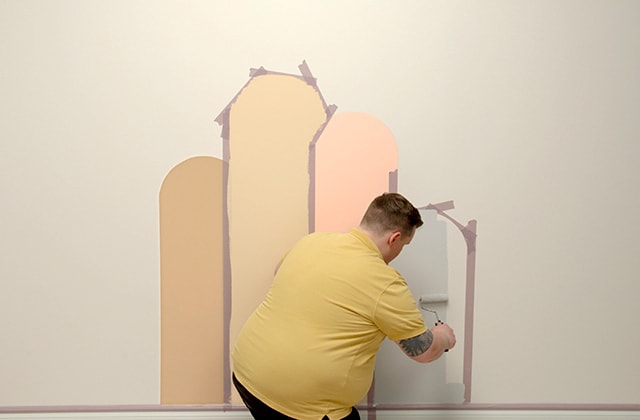 Man painting an arch on a wall