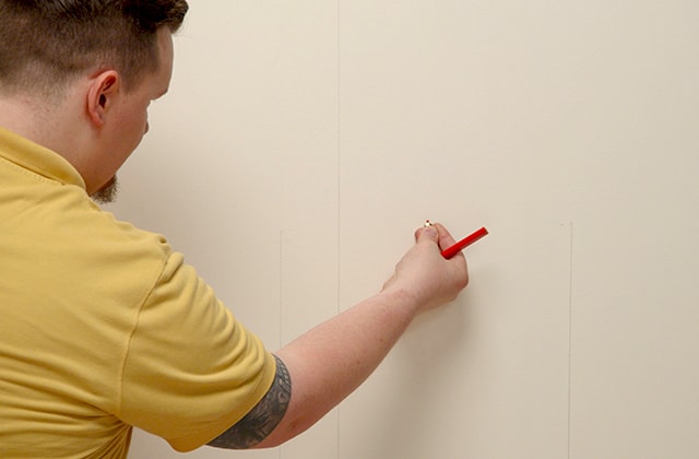 Man thumbtacking a string on a wall