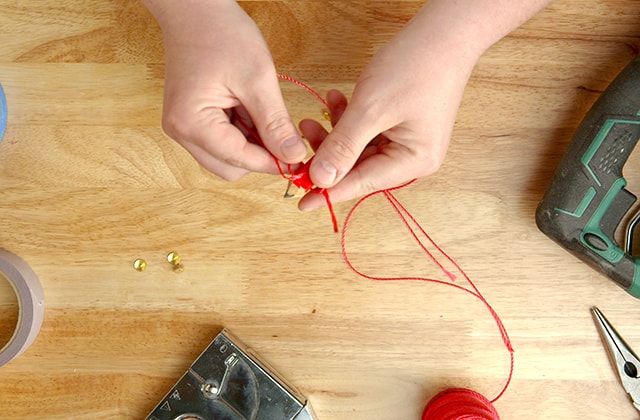 Man tying a string onto a pencil 
