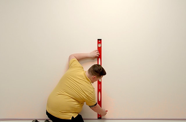 Man using a level to trace a line
